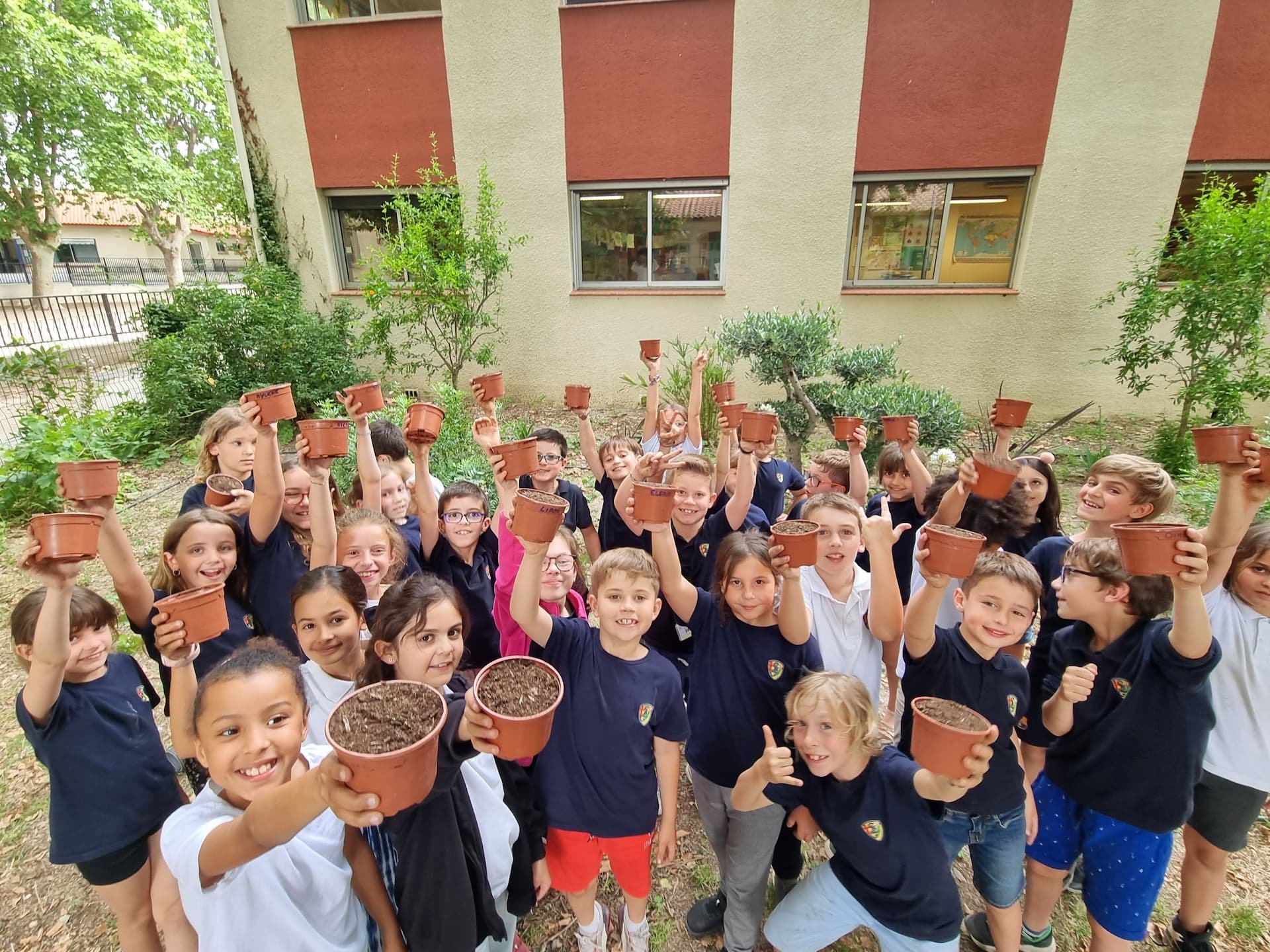 Groupe d'enfants montrant des pots remplis de terre
