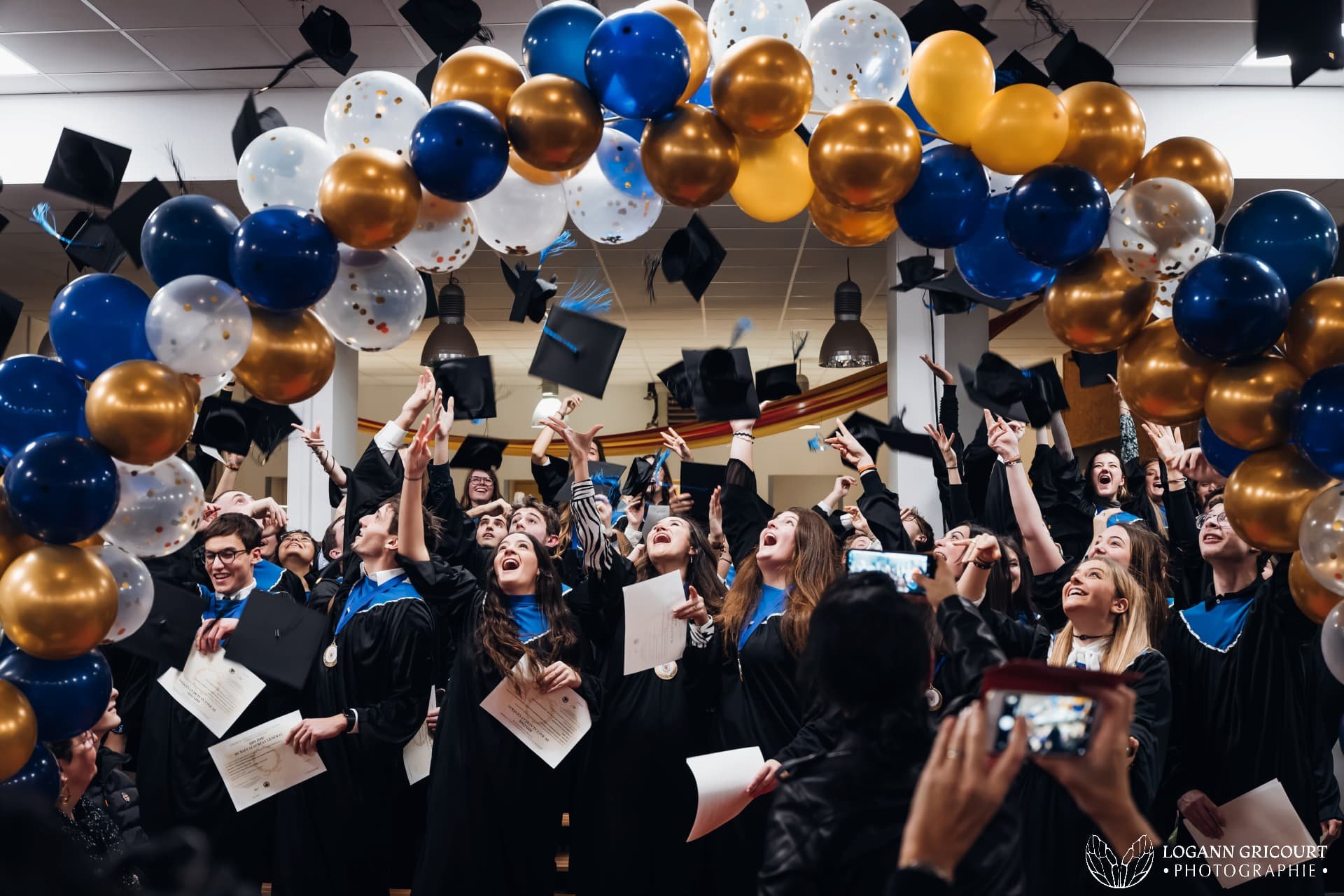 Etudiants diplômés lançant leurs chapeaux en l'air sous une arche de ballons