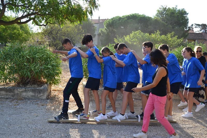 Groupe de collégiens se tenant par les épaules, l'un derrière l'autre